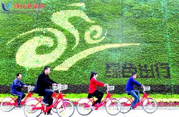 市民騎公共自行車路過市人民廣場(chǎng)一處花壇。記者 張馳